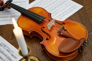 Fototapeta premium Classical Music Serenade Under Candlelight with Violin and Sheet Music on Wooden Tabletop