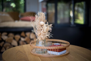 Des fleurs séchées dans un panier en rotin posé sur une table en bois dans une maison