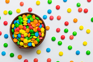 Multicolored candies in a bowl on a colored background. birthday and holiday concept. Top view with copy space