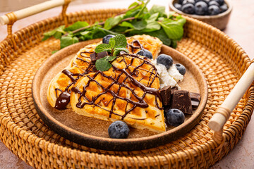 Thin pancakes with chocolate spread and blueberries on the light background close up