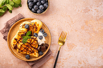 Thin pancakes with chocolate spread and blueberries on the light background top view copy space for text