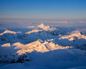 Obraz premium The first rays of the sun illuminate the mountains of the Main Caucasian range. View from Pastukhov cliffs on the Mt. Elbrus slope in Russia.