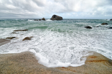 Closeup of a wave foam on a rocky beach during stormy day