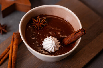 A bowl of hot chocolate with cinnamon and spices on the Christmas table. Hot winter drink
