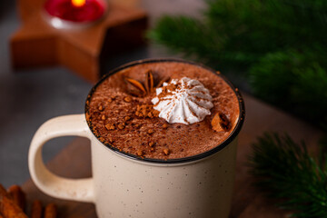 A cup of hot chocolate with cinnamon and spices on the Christmas table. Hot winter drink close up