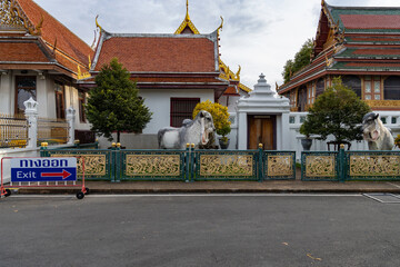 Temple courtyard in Bangkok with traditional architecture, cow statues and exit sign in Thai and English