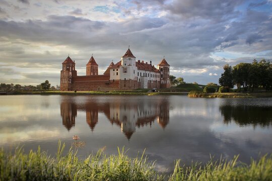 Mir Castle. A castle on the shore of a lake. A summer landscape. Sunset. An ancient medieval fortress. Travel. An architectural monument of the Middle Ages - Mir Castle, Belarus.