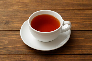 Cup of brewed black loose leaf tea, aromatic traditional beverage on a wooden table