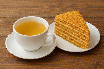 A cup of Milk Oolong tea and a piece of honey cake on a wooden table