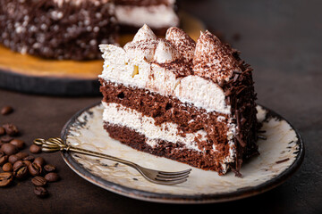 A piece of tiramisu cake with chocolate and whipped cream on dark background