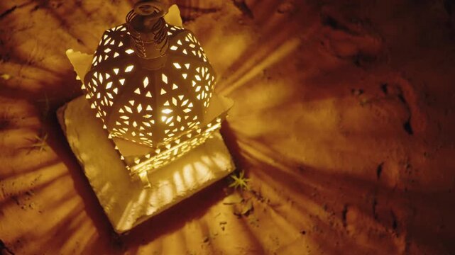 Warm light from an ornate Moroccan lantern glows on the desert sand at night. This atmospheric scene evokes a sense of mystery and tranquility in the vast Sahara Desert.