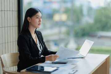 Asian office woman focused on computer work, typing and concentrating on business tasks.