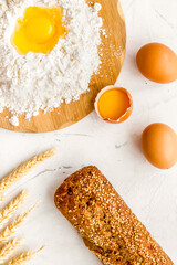 Make bread concept. Bread near wheat ears, flour and eggs on white background top view