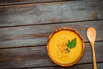 Pumpkin soup on dark wooden background top view copy space
