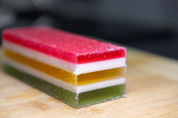 Vibrant layered jelly dessert with colorful red, yellow, green, and white sections, coated in sparkling sugar crystals, perfect sweet treat or festive celebration