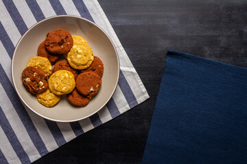 Bowl with some cookies and blue striped table cloth on black chalkboard texture. Flat lay. Top view. Food concept.