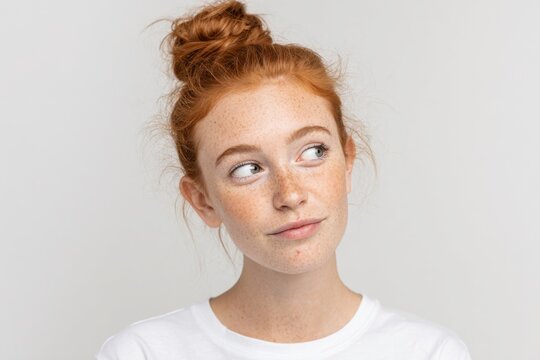 Close-up of a young red-haired girl with freckles and blue eyes looking to side.