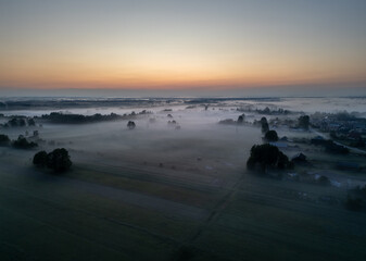 Aerial view of fields and meadows during foggy evening in Gmina Lochow, Poland