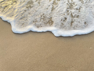 White foam waves background on sandy beach 
