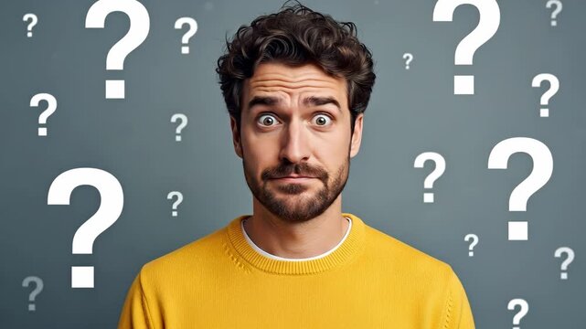 Confused Man with Question Marks - A young man with curly brown hair, wearing a yellow sweater, looks confused. Large white question marks float around him against a gray background.