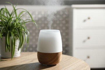 One stylish aroma lamp and houseplant on wooden table indoors, closeup