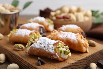 Delicious cannoli with ricotta cheese, peanuts, pistachios, chocolate and powdered sugar on table, closeup