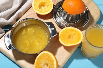 Freshly squeezed orange juice, fruits and juicer on blue wooden table, closeup