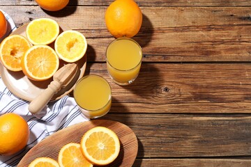 Freshly squeezed orange juice, fruits and juicer on wooden table, flat lay. Space for text