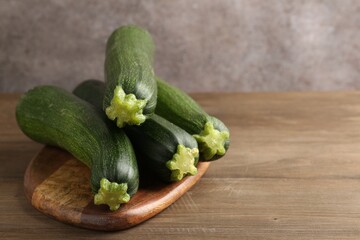 Fresh ripe zucchinis on wooden table, closeup. Space for text