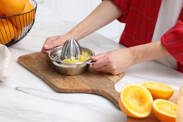 Making orange juice. Woman with juicer at white marble table indoors, closeup