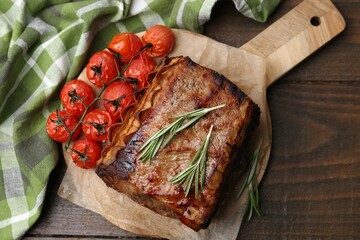 Delicious roast beef with rosemary and tomatoes on wooden table, top view