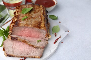 Delicious baked beef meat, spices and water with lime on light table, closeup. Space for text