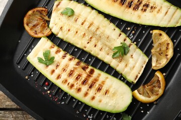 Delicious grilled courgette slices with spices and lemon in pan on table, top view