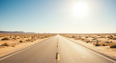 A long, straight asphalt road stretches into the distance through a dry, desert landscape under a bright, clear blue sky and intense sunlight.