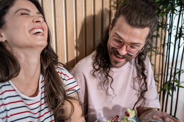 Happy couple laughing and eating a salad together at home