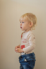 Side view of blond little boy in Christmas shirt standing and looking forward during holidays