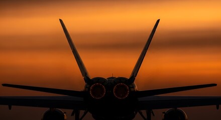 Silhouette of a powerful jet fighter aircraft with afterburners glowing against a vibrant orange sunset sky, showcasing its twin tail fins and wings.