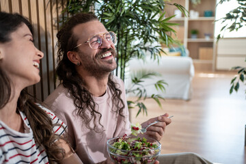 Obraz premium Couple laughing and eating salad at home