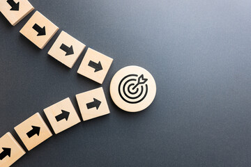Wooden arrows from multiple directions converging toward a target icon symbolizing team alignment, strategic direction, shared goal, collective effort, and effective planning