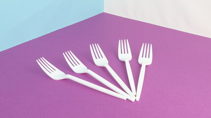 Plastic forks and abstract still life with white forks on a purple background