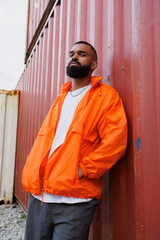 Confident african american man in windbreaker jacket looking at camera in port © Dmytro Hai