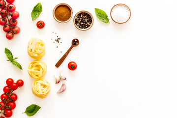 Fettuccine with ingredients for cooking pasta - tomatoes and basil with garlic - on a white background, top view. Flat lay