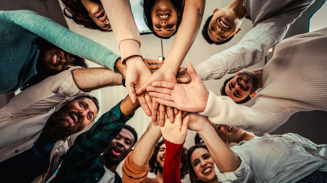 Young happy people stacking hands together outcoor - Community of multiracial international people supporting each other - Diverse culture