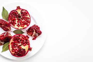 Top view of fresh ripe pomegranate and pieces on plate for eating, top view.