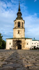 Obraz premium Ancient church tower, stonework, and paved plaza