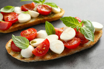 Delicious sandwiches with mozzarella cheese, tomatoes and basil on grey textured table, closeup