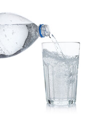 Pouring refreshing soda water from bottle into glass on white background