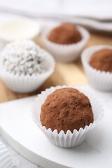 Delicious homemade candies with cocoa powder and coconut flakes on table, closeup