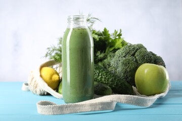 Tasty juice in glass bottle and ingredients on light blue wooden table, closeup