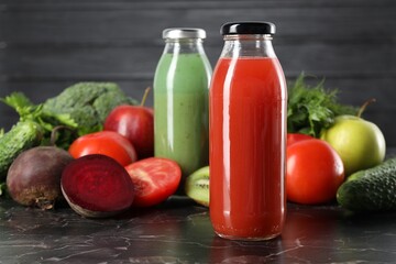 Tasty juices in glass bottles and ingredients on black marble table, closeup